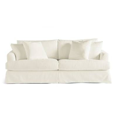 a white couch with lots of pillows on it's back and side cushions in the middle