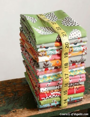 a stack of cloths with a measuring tape in front of them on top of a wooden table