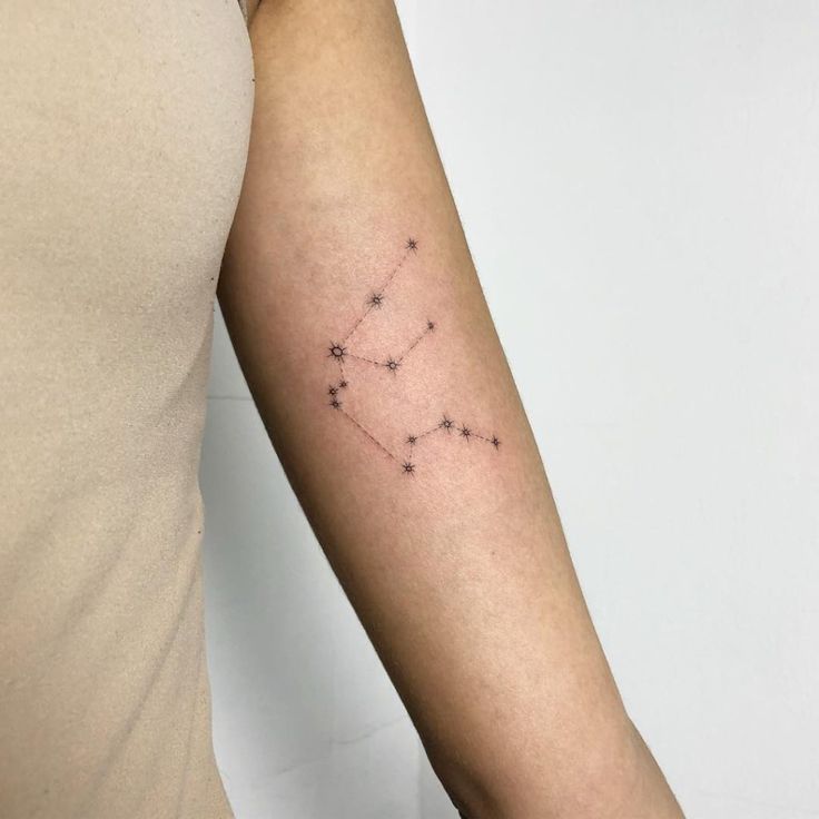 a woman's arm with a small zodiac sign tattoo on the left side of her arm