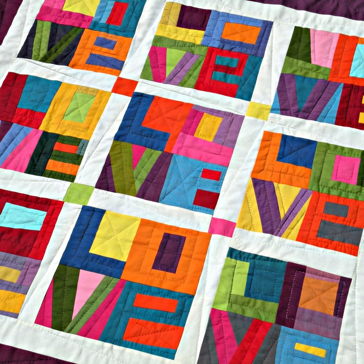 a colorful quilt is on display in the middle of a tablecloth with squares and rectangles all over it