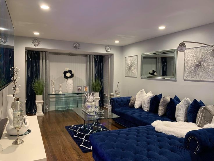 a living room filled with blue couches and white pillows on top of a hard wood floor