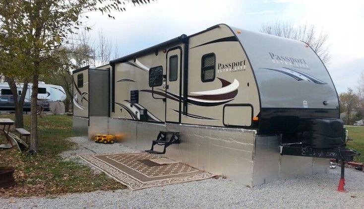 an rv is parked in the gravel near trees