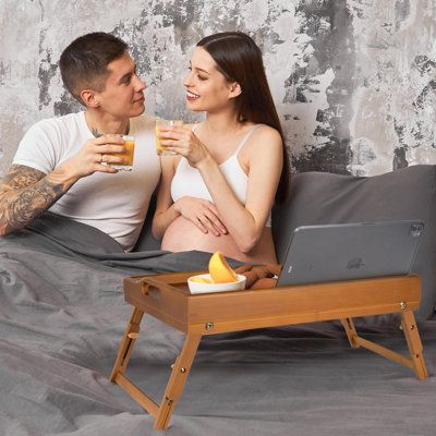 a man and woman sitting on a bed drinking orange juice while looking at each other