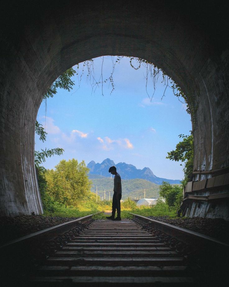 a man standing in the middle of a tunnel with mountains in the backgroud