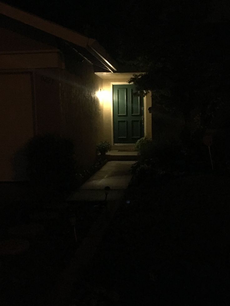 a house is lit up at night with the door open and light shining on it