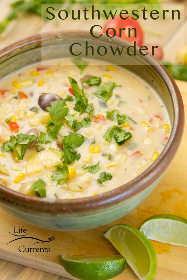 a close up of a bowl of corn chowder with limes on the side