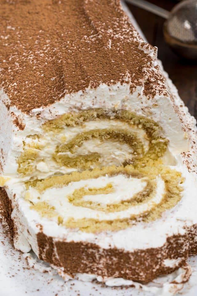 a cake with white frosting and brown sprinkles sitting on a plate