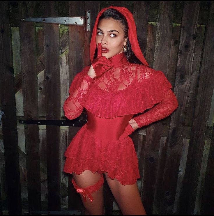 a woman in a red dress and hoodie posing with her hands on her face