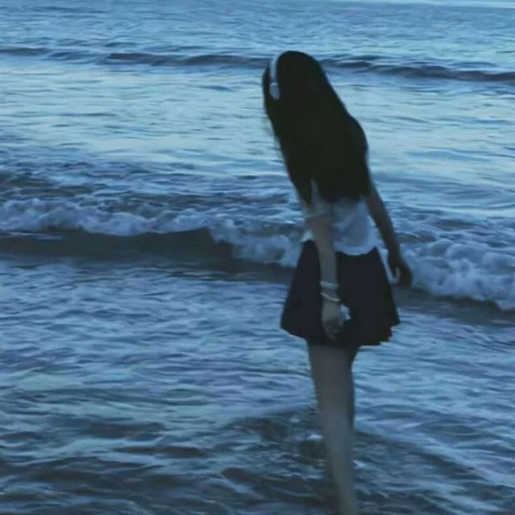 a woman standing in the ocean with her back to the camera