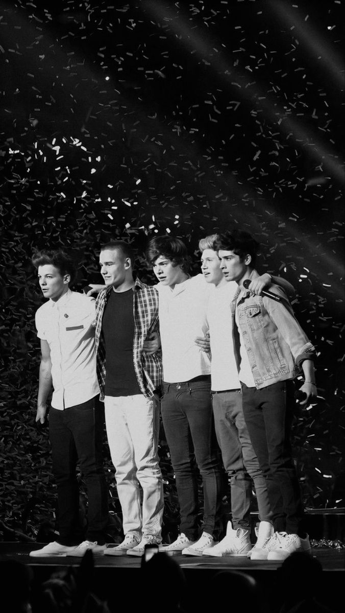 four young men standing on a stage with confetti in the background