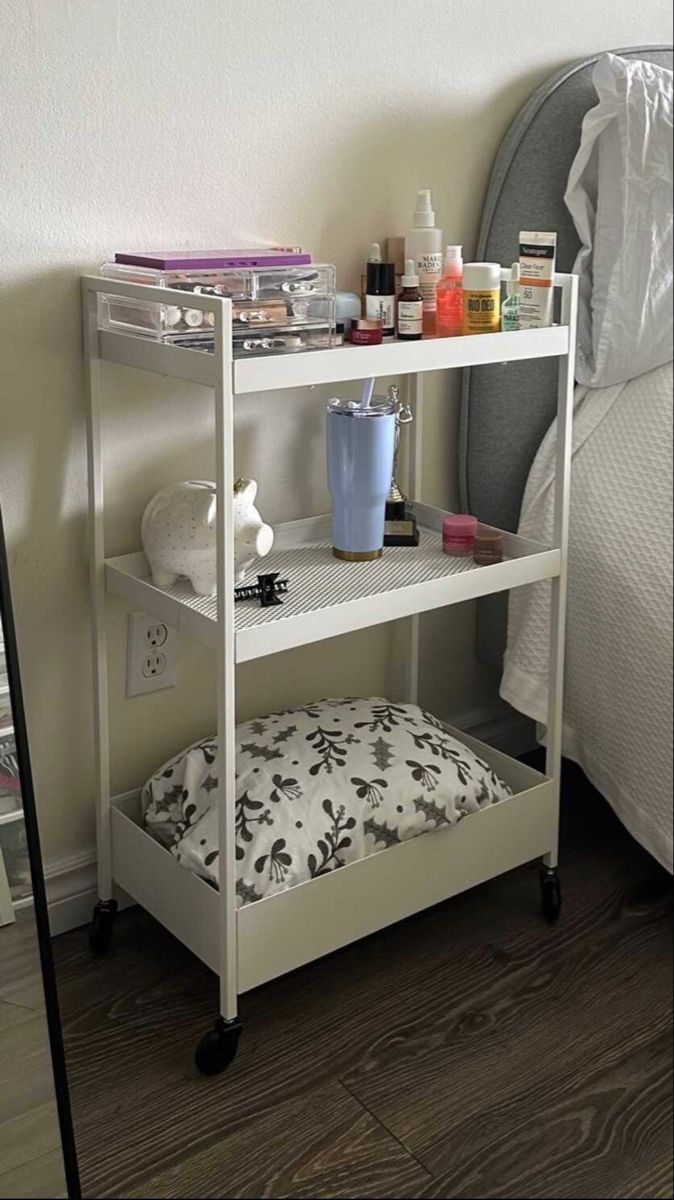 a white shelf next to a bed in a room