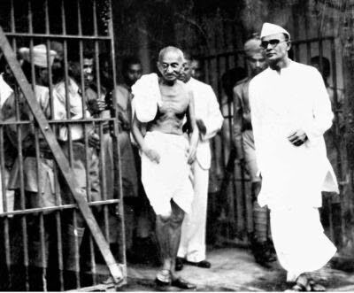 two men standing next to each other in front of a jail cell with bars on it