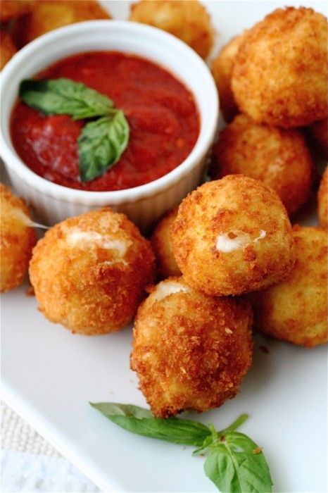 some fried food on a white plate next to a bowl of tomato sauce