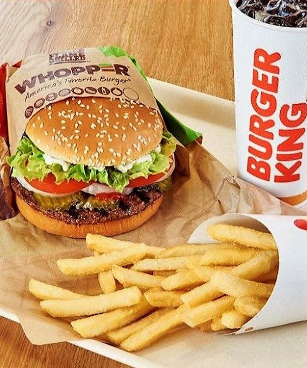 a burger and fries on a tray next to a cup of kroger soda