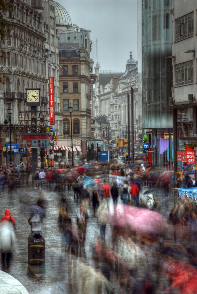 many people are walking down the street with umbrellas