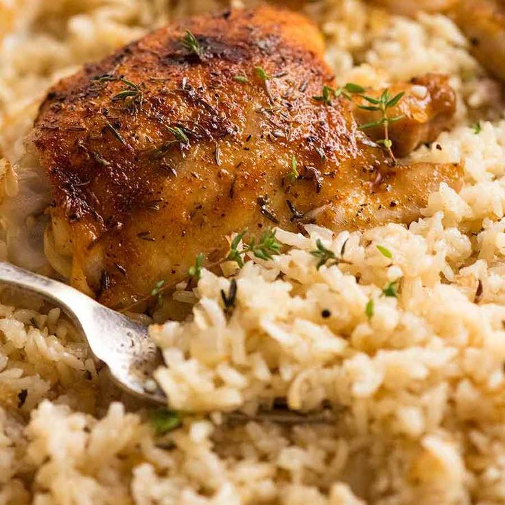 a close up of rice and chicken on a plate with a fork in the middle