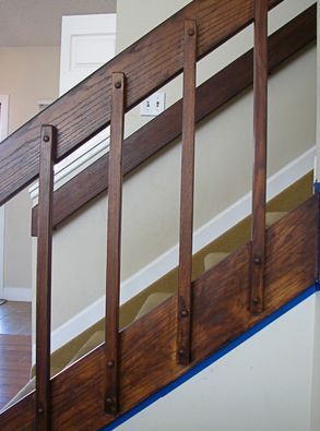 the bottom half of a stair rail with wood slats on it and blue tape