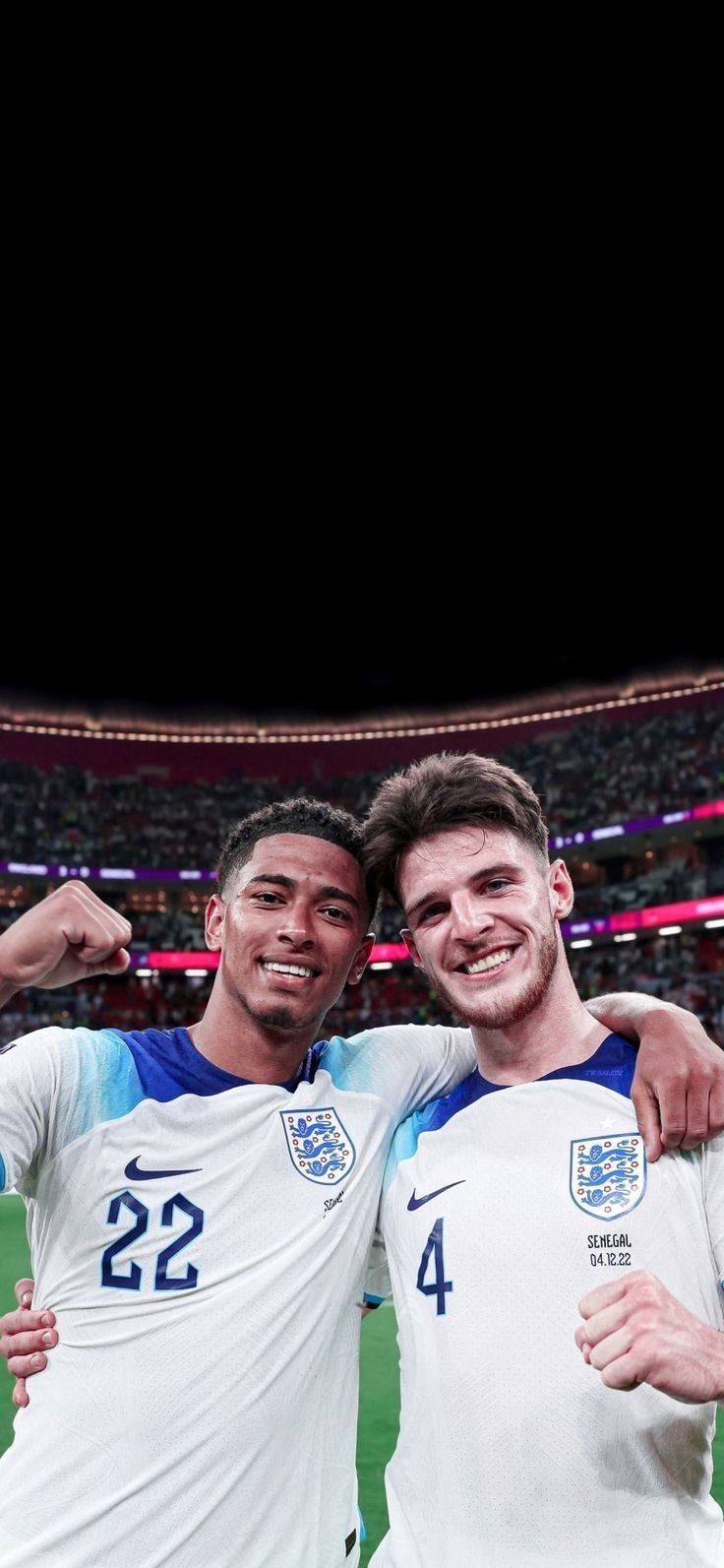 two men standing next to each other in front of a crowd at a soccer game