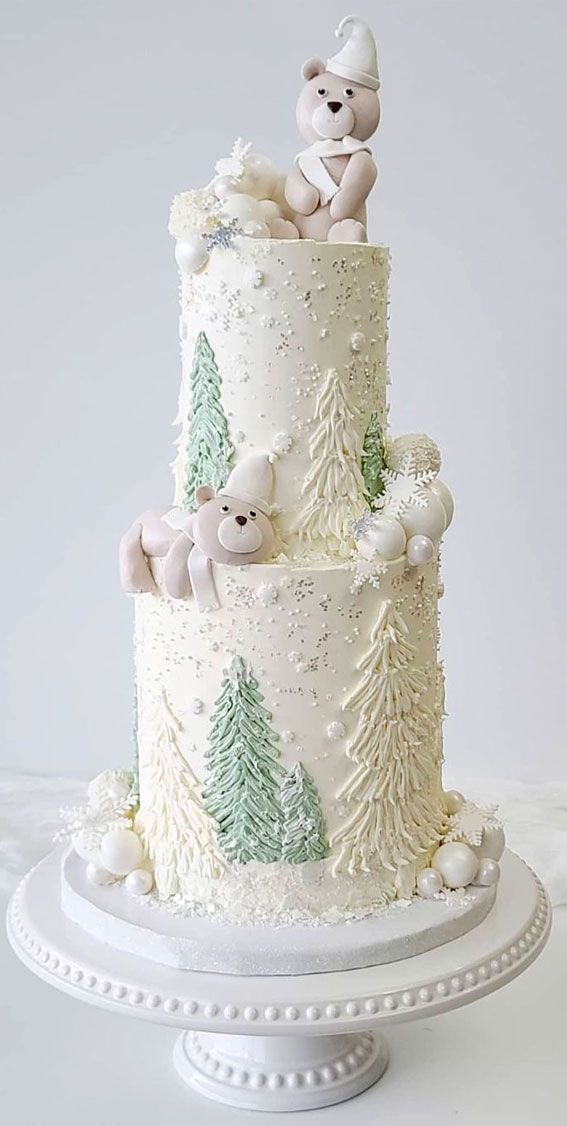 a three tiered cake decorated with white frosting and teddy bears