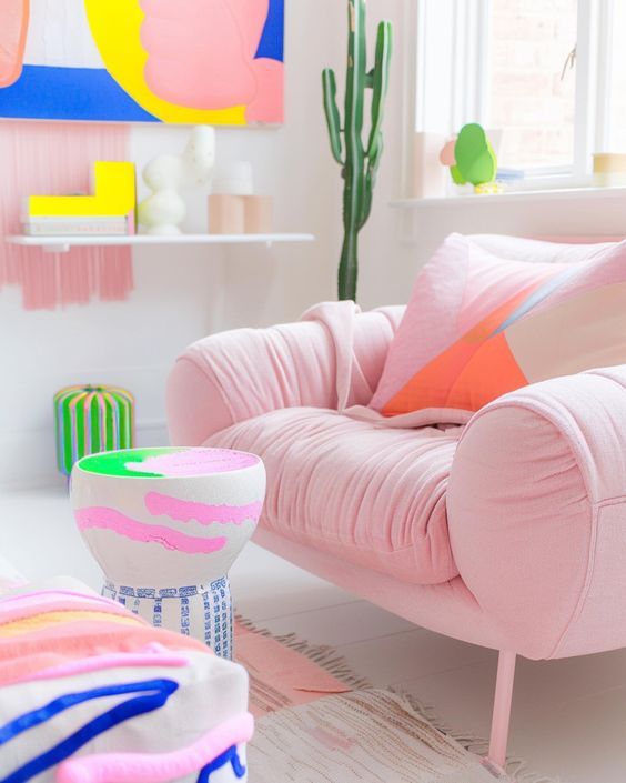 a living room filled with pink furniture and colorful pillows on top of it's covers