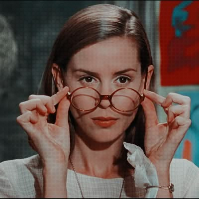 a woman holding up her glasses in front of her face