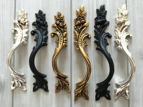 four different styles of door handles on a white wooden surface with black and gold accents