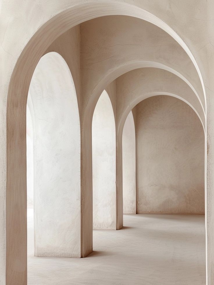 an empty room with arches and columns in the center, white walls are lined with light colored concrete