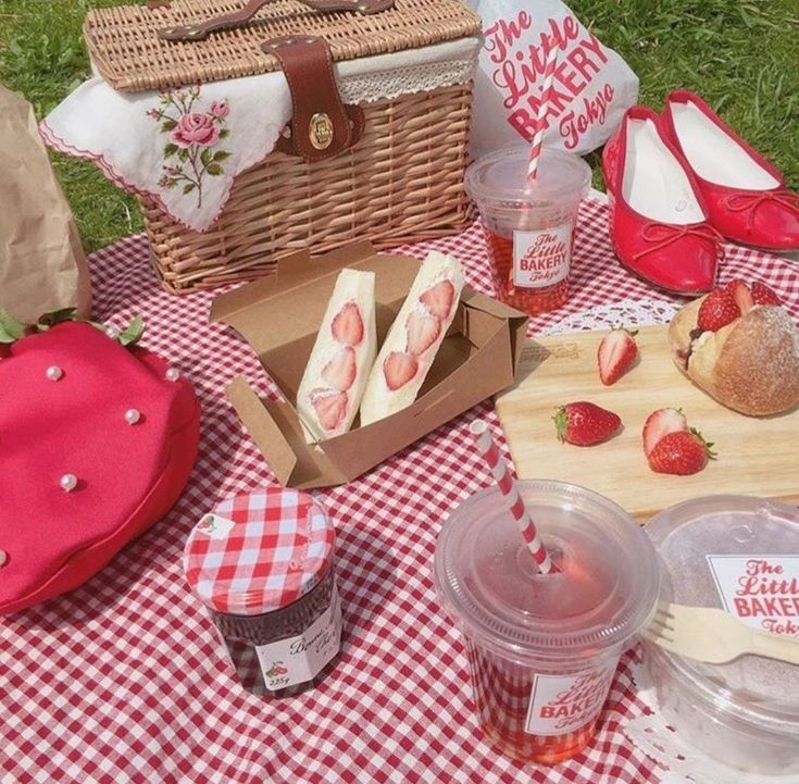 a picnic table with strawberries, cake and ice cream in baskets on the grass