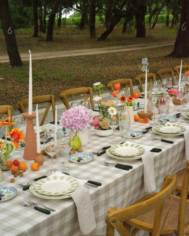 a long table with plates and flowers on it is set for an outdoor dinner party