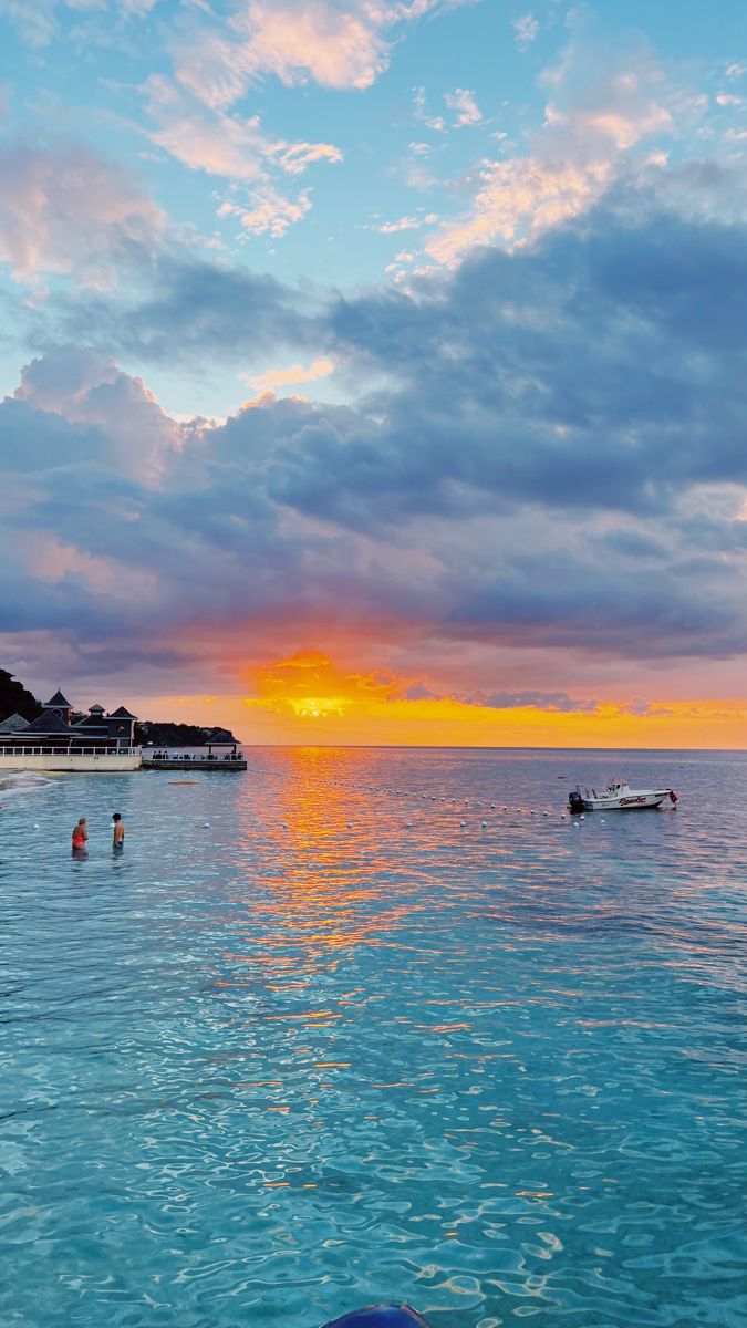 people are swimming in the ocean at sunset