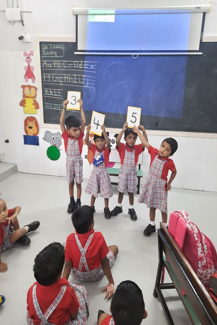 several children holding up signs in front of a blackboard