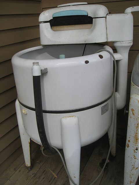 an old white water tank sitting on top of a wooden floor next to a building