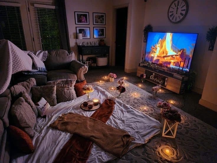 a living room with candles on the floor and a television in the corner that is turned on