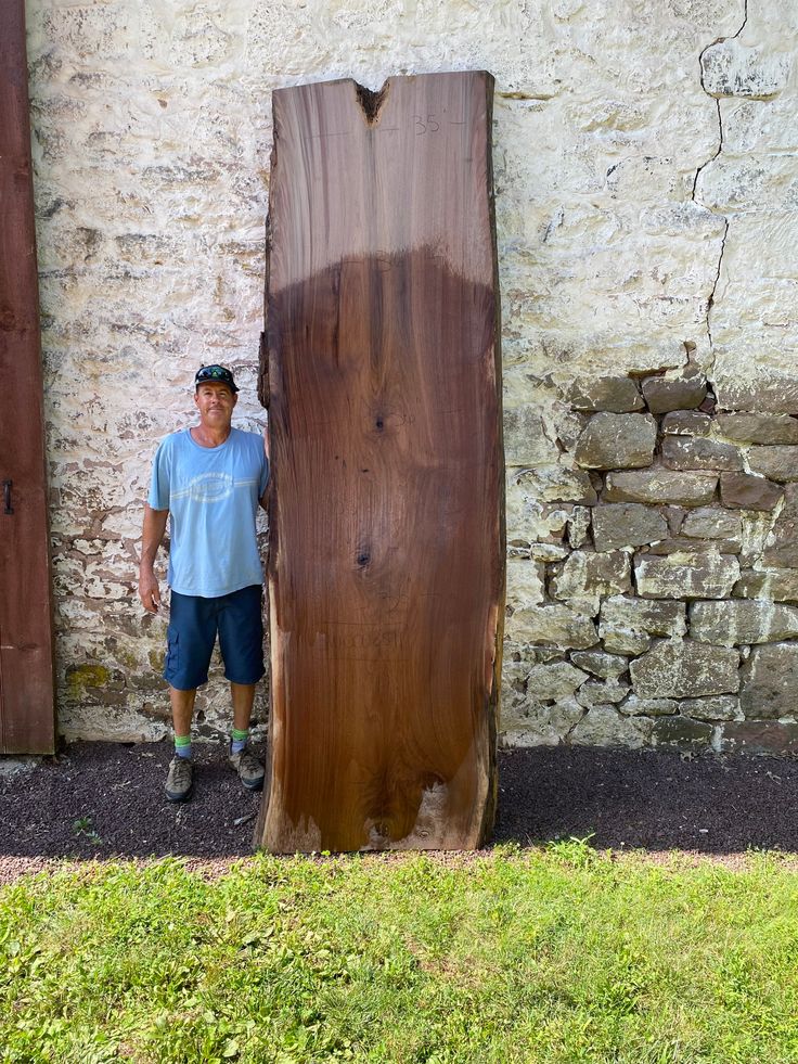 a man standing next to a large piece of wood