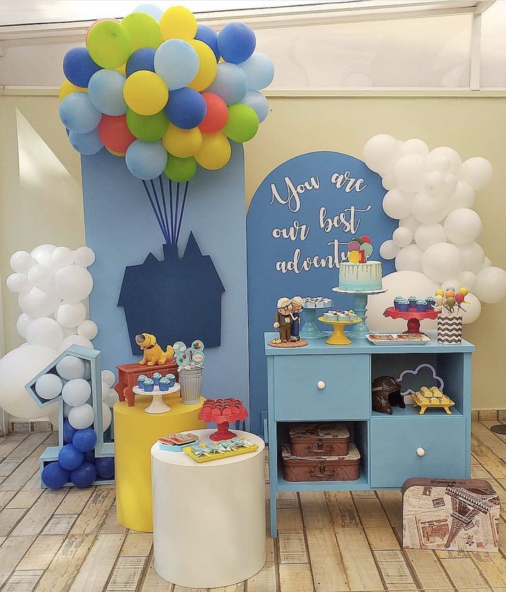 a birthday party with balloons and decorations on the floor, including a blue cabinet for children's toys