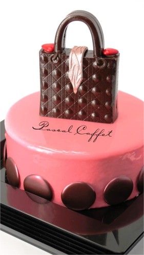 a pink cake with a handbag on top and chocolate dots around the edges,