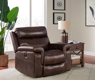 a brown recliner chair sitting in a living room next to a table and potted plant