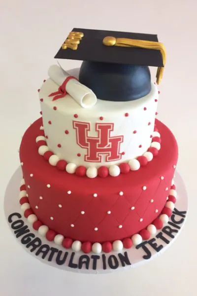 a graduation cake is decorated with red and white icing, topped with a black cap and tassel