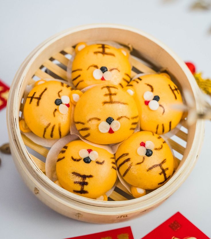 a basket filled with yellow tiger cookies on top of a white table next to red cards