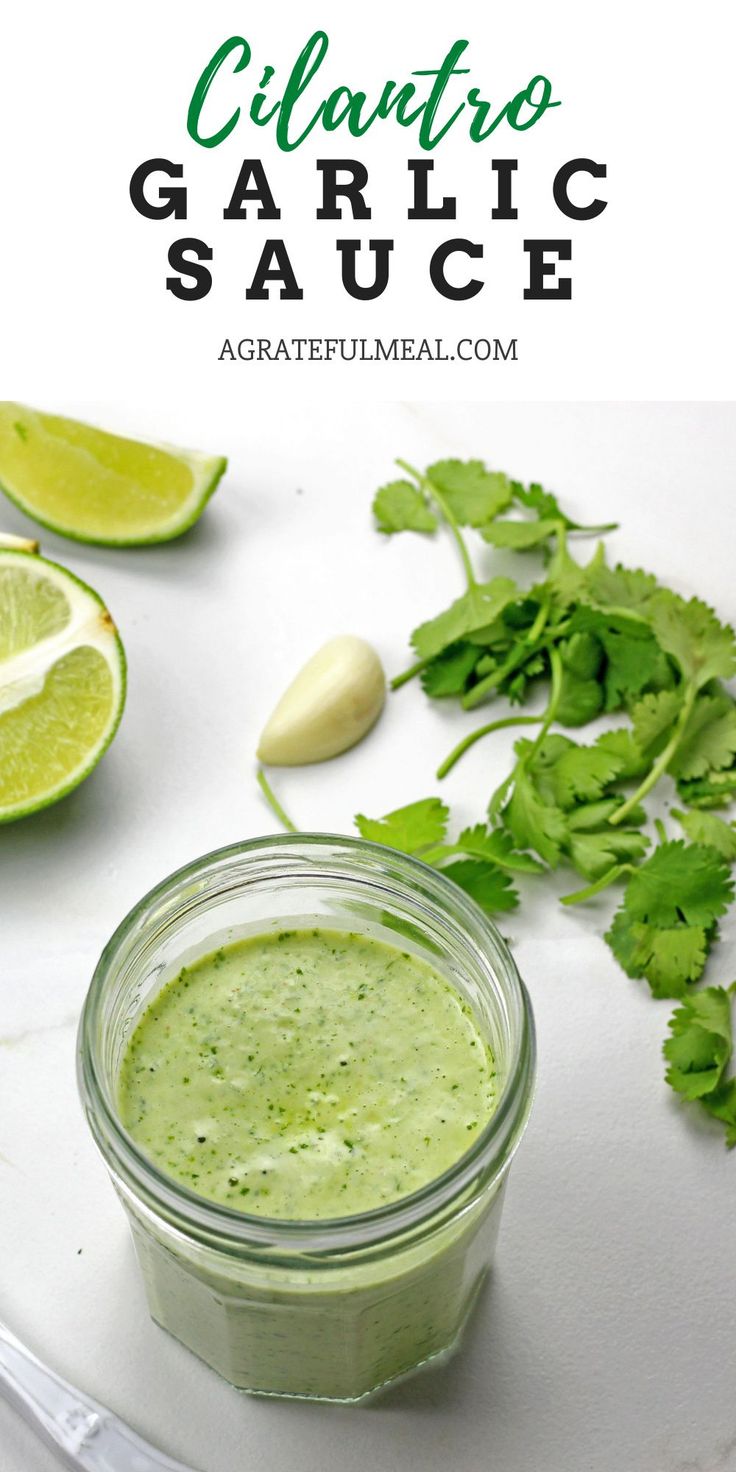 cilantro garlic sauce in a glass jar with limes around it