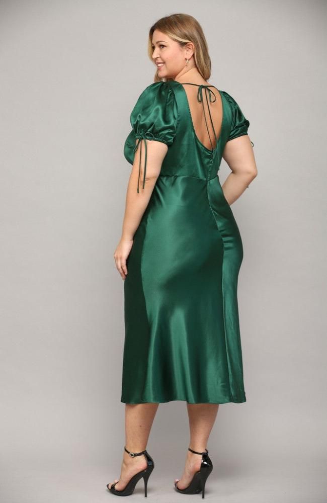 a woman wearing a green satin dress with open back and tie at the neckline