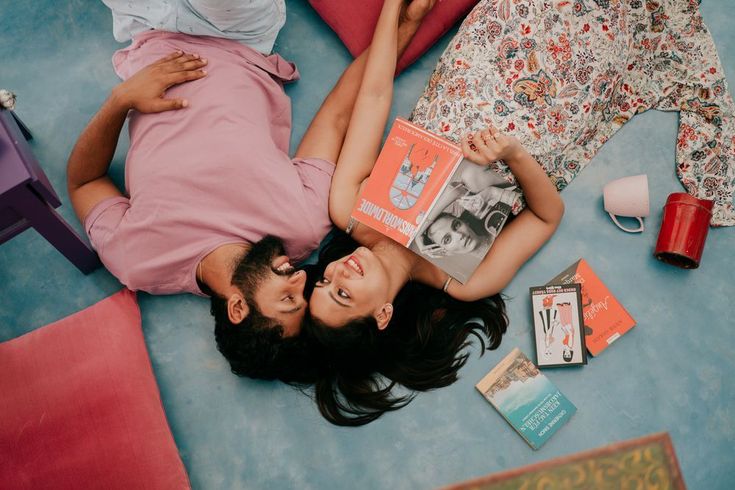 a man and woman laying on the floor with books