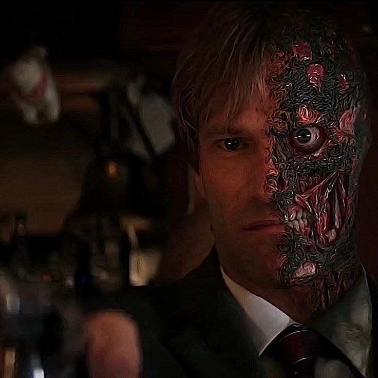 a man in a suit and tie has his face painted like a demon with red eyes