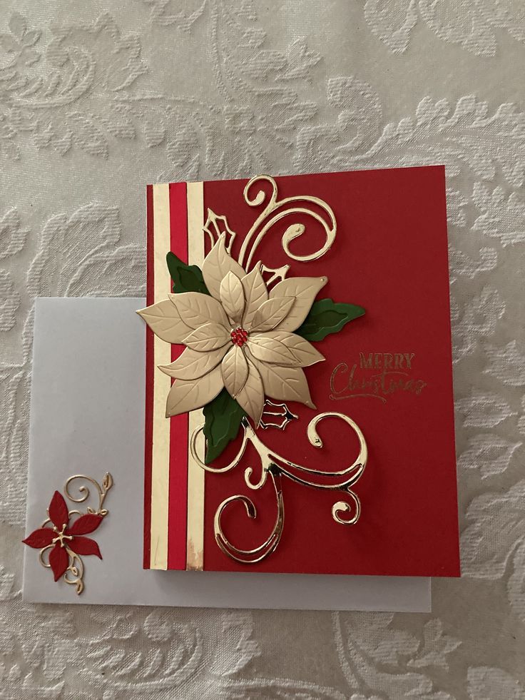 a red and white christmas card with poinsettis on the front, gold trim around the edges