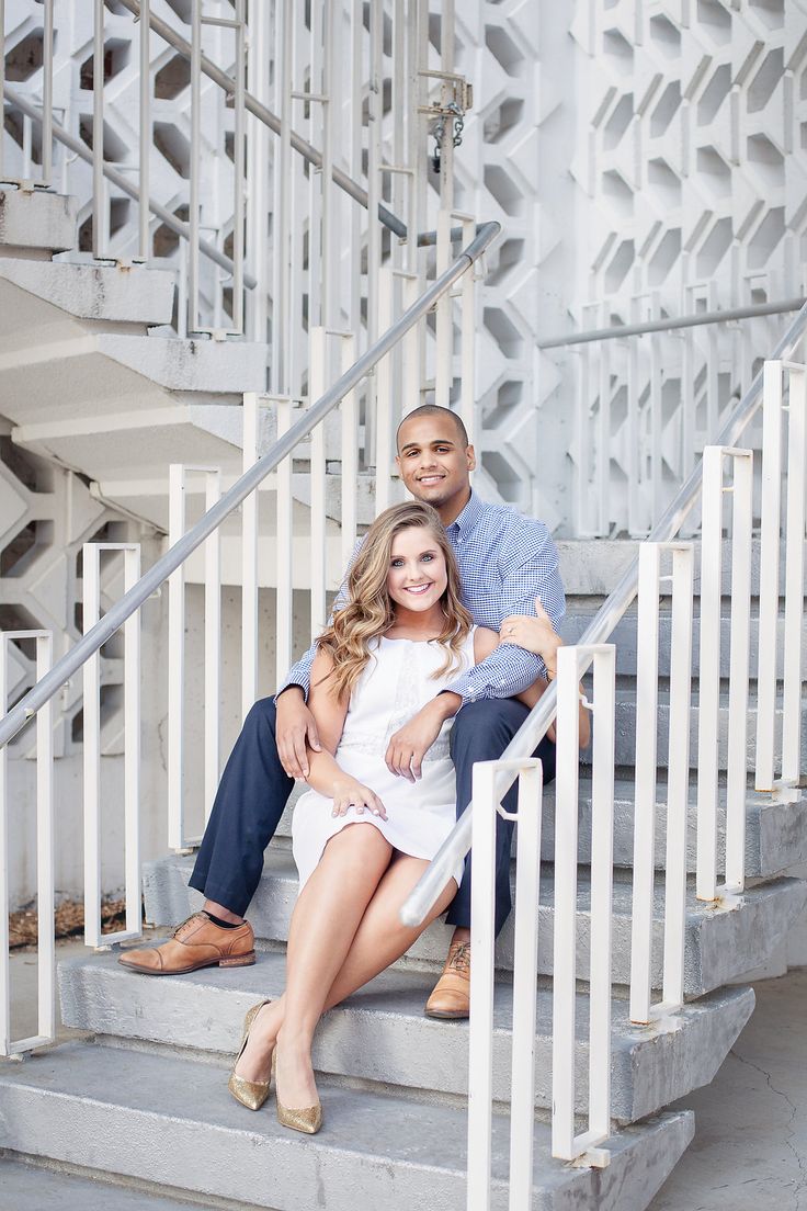 a man and woman sitting on the steps of a white building with their arms around each other