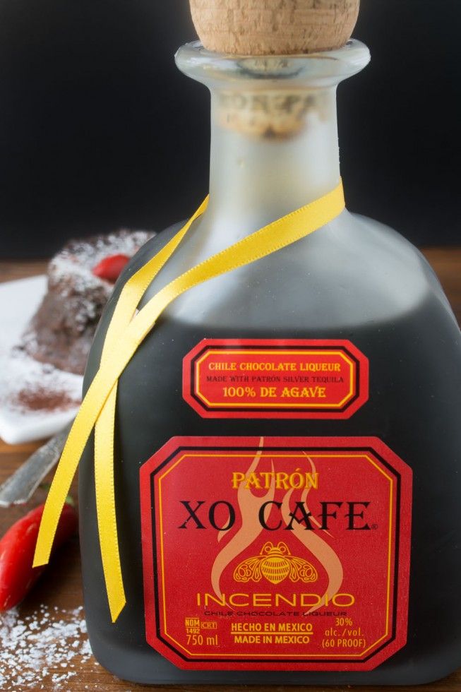 a bottle of liquor sitting on top of a table next to a piece of cake