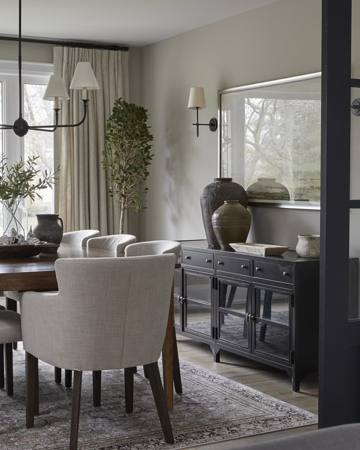 a dining room table with chairs and a vase on top of it in front of a window