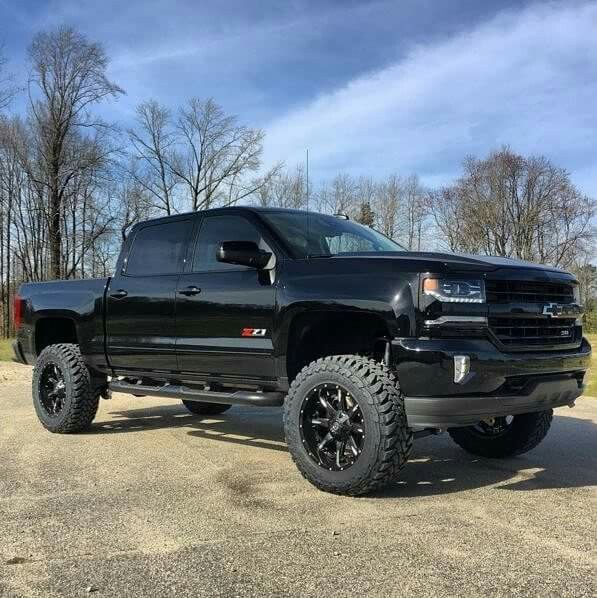 a black truck parked on top of a gravel road