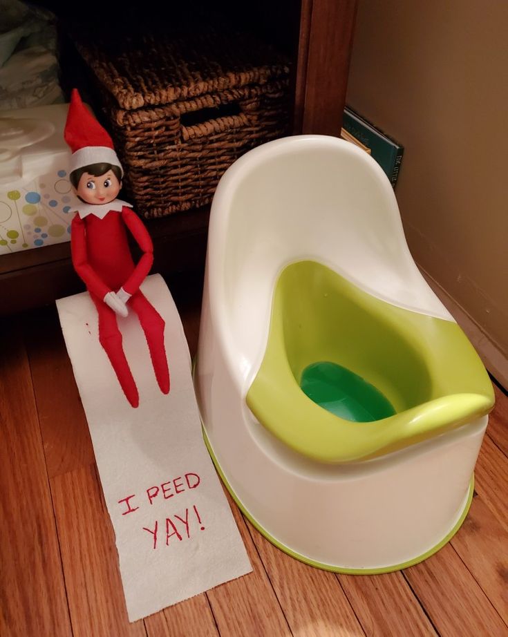 an elf sitting on top of a potty seat next to a sign that says i peed ya