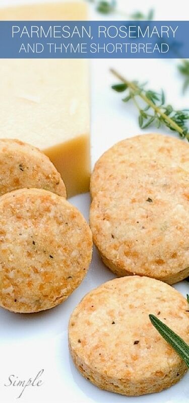 three shortbreads on a white plate next to a block of cheese and herbs